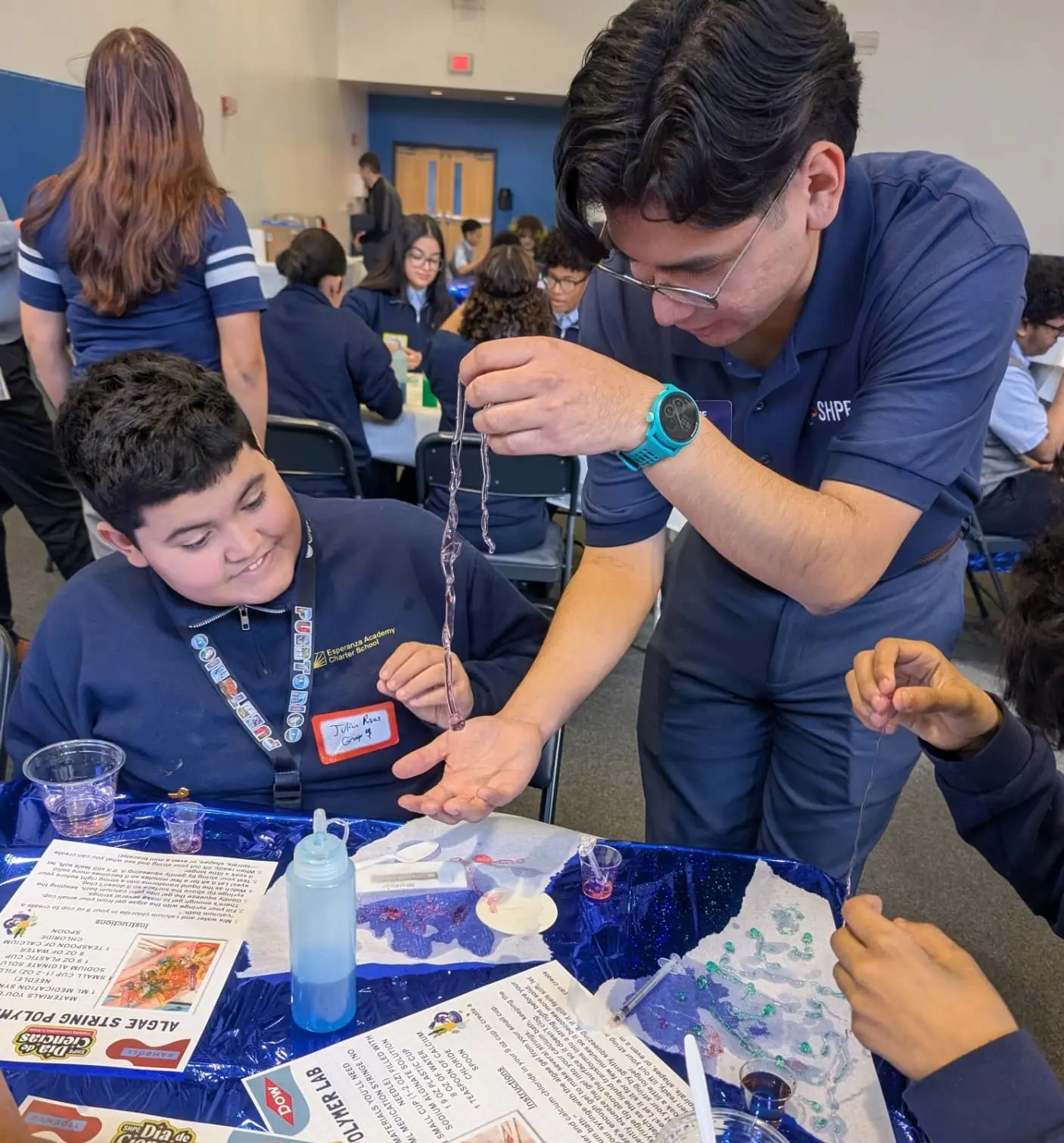 SHPE volunteer leads a student through a hands-on algae string polymer lab at Día de Ciencias.