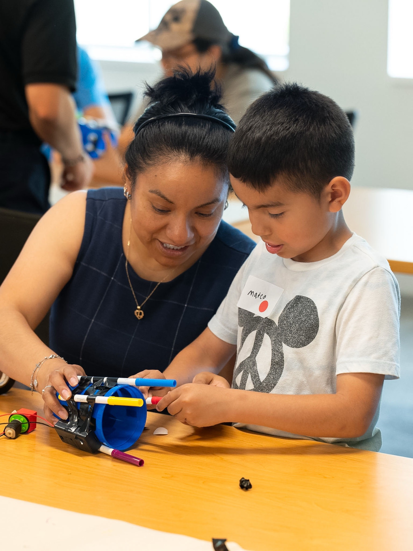 A volunteer and student work together on a hands-on STEM project during Familia Day at the SHPE National Convention.